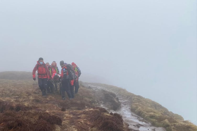 The mountain rescue team stretchering the woman off the mountain