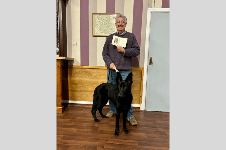 Ted Tidman holding the Christmas card alongside guide dog puppy, Fisher