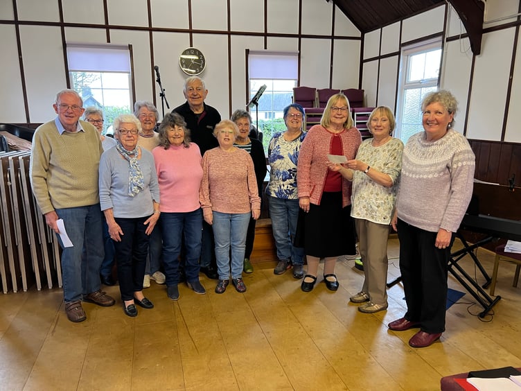 Vera Buckler, leader of the Bracken Trust Singers, accepts a £463 donation from Cynthia Shepperd, Chair of the Powys WI Committee, during a presentation at Llanyre Church Hall on April 15