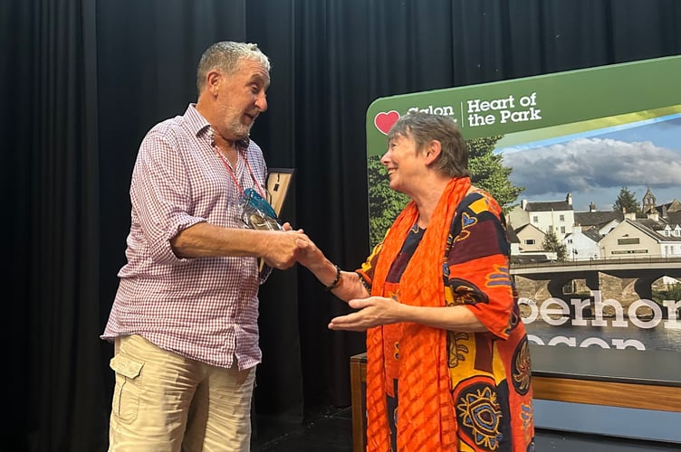 Clive Morris accepts the Volunteer of the Year Award from Cllr Sian Drinan on behalf of his wife, Taniya Morris MBE