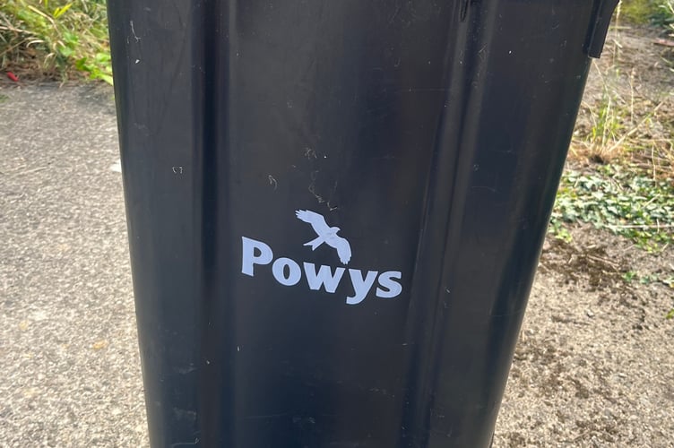 A black residual waste bin in Powys