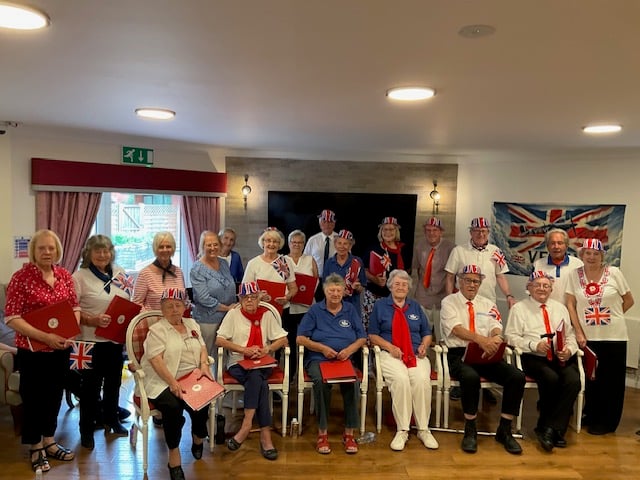 The Bracken Trust Singers perform at Crosfield House, dressed in their blue, red, and white outfits
