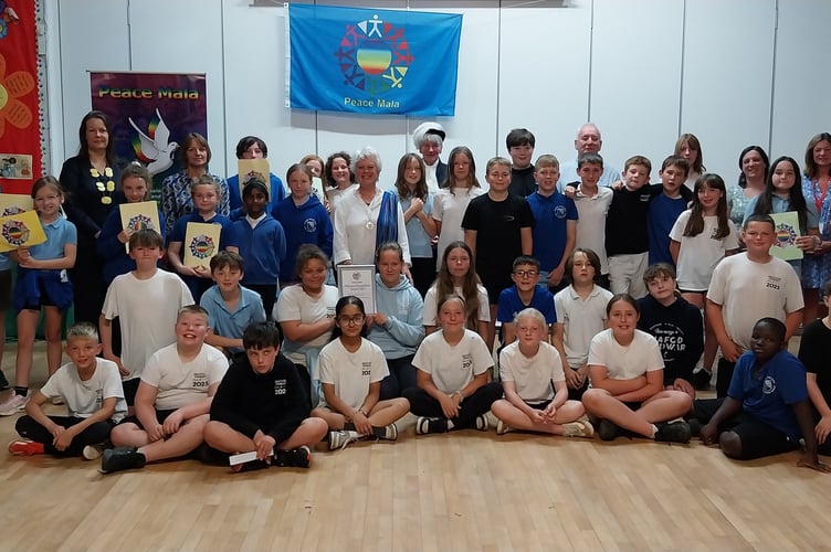 Pupils and staff from Rhayader Church in Wales Primary School celebrate receiving the Peace Mala Platinum Award