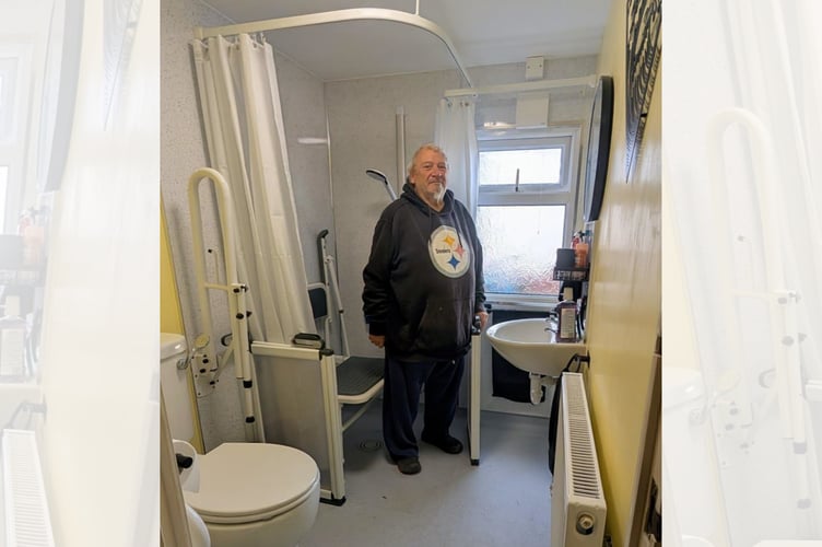 Stephen Fleming in his improved bathroom, which now includes a level access shower, a wall-mounted drop-down shower seat, raised-height toilet and drop-down rails, next to the toilet.