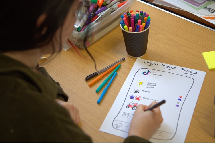 A child filling in a response to 'drawing your feed' during a Ceredigion Youth Service Focus Group session