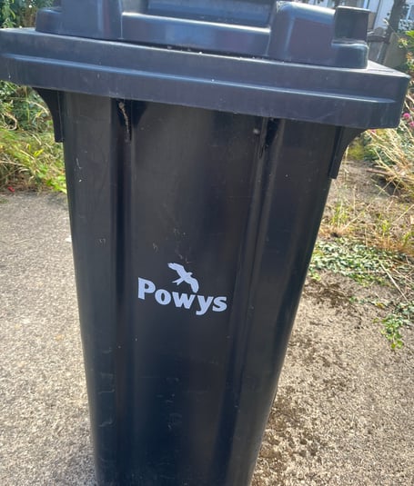 A black residual waste bin in Powys