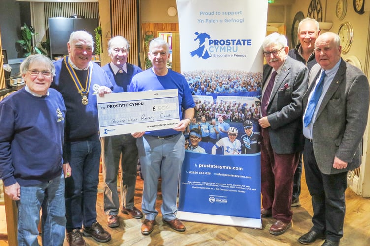 Rob Healey receiving cheque from Builth Rotary President, Hugh Garner, joined by members of the Rotary who participated in Movember