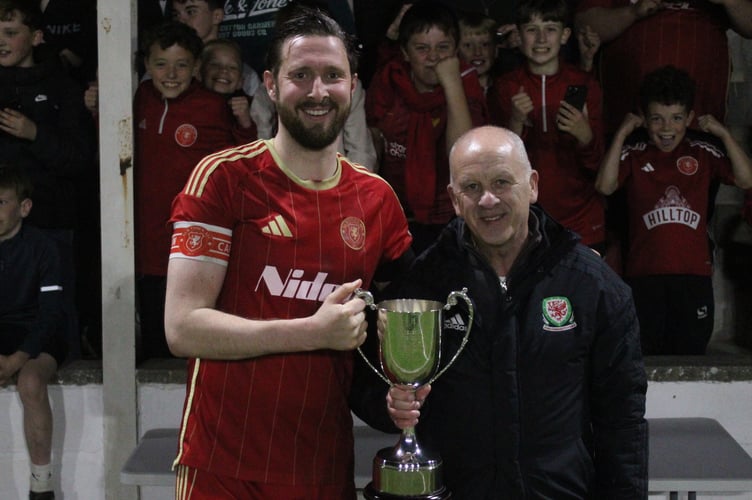Newtown skipper Kieran Mills-Evans receives the trophy from Central Wales FA councillor Kevin Moon