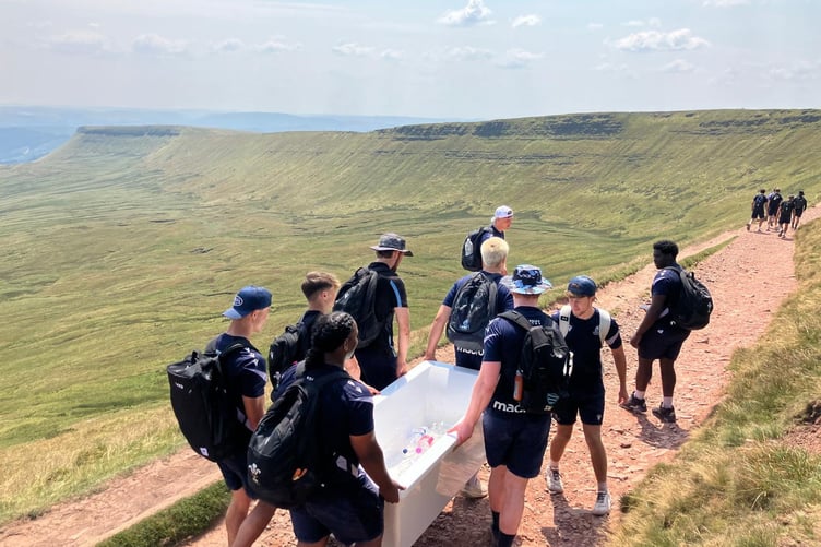 Cardiff Rugby team helping the National Trust rangers retrieve a bath tub which had been left up Pen Y Fan. A man has apologised for taking a bath tub up a mountain - and leaving it there.
Tom Christopher, 25, carried the brand new bath tub up the highest peak in South Wales in an attempt to break the record for the 'world's highest bath'. After he took his epic bath, the content creator from Wales said he planned on leaving the tub up Peny Y Fan for 48 hours - so others could enjoy it. However, Cardiff rugby players who visited the peak 24 hours later decided to remove the tub themselves after assuming it had been dumped. The team said they carried it all the way back down the mountain - and slammed the "mindless" action.