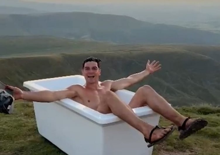 Tom Christopher, 25, carried the tub up Pen Y Fan in an attempt to break the record for the 'world's highest bath'. // A man has apologised for taking a bath up a 3,000ft mountain - and leaving it there. Tom Christopher, 25, carried the tub up Pen Y Fan in an attempt to break the record for the 'world's highest bath'. The content creator had a soak and said he planned leaving it up the 886m (2,907 feet) highest peak in South Wales for 48 hours - so others could enjoy it. But Cardiff rugby players who visited the peak 24 hours later decided to remove the tub themselves after assuming it had been dumped. The team said they carried it all the way back down the mountain - and slammed the "mindless" action.