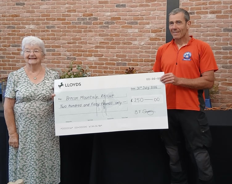 Brecon Floral Society president Vera Davies presents a £250 cheque to Brecon Mountain Rescue volunteer Mark Jones after the society chose the charity as its chosen cause for 2026