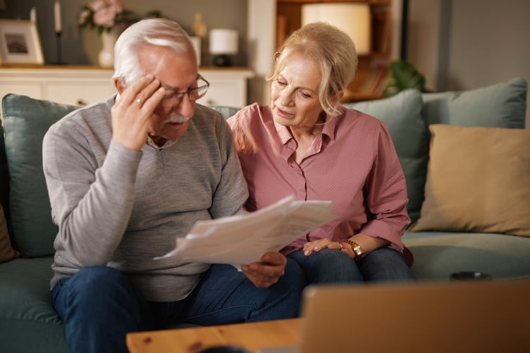 Senior couple looking concerned while reading paperwork, possibly related to finances or insurance